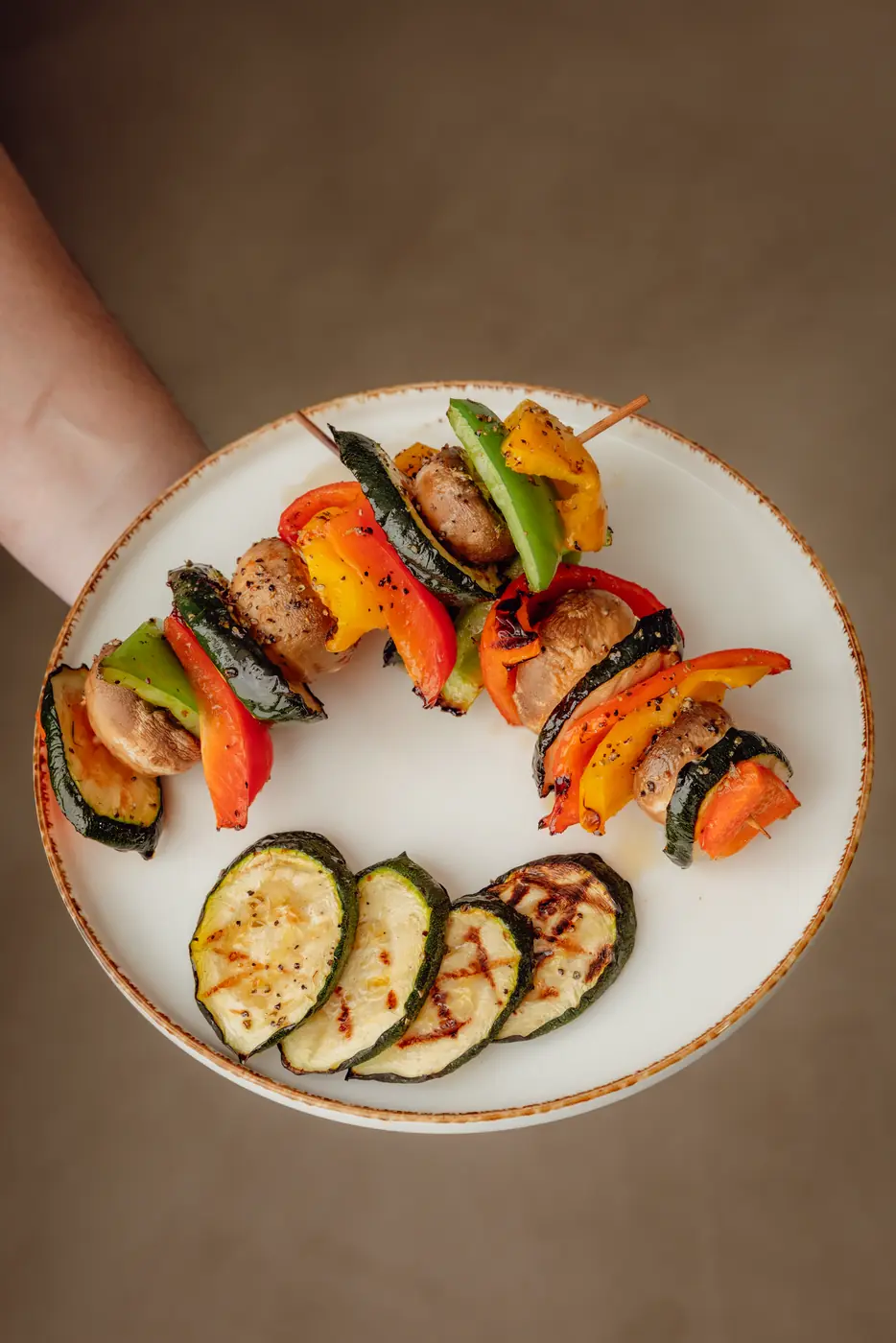 Groentespiesen met paprika en champignon en gegrilde courgette op een bord